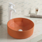 Lavandino rotondo ceramico liscio del bagno sopra il contro lavabo arancio del piano d'appoggio